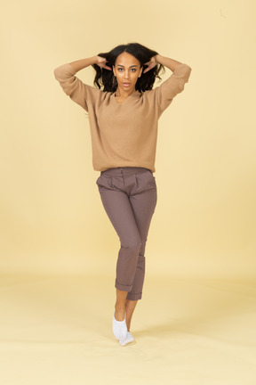 Front view of a dark-skinned young lady fixing her hair