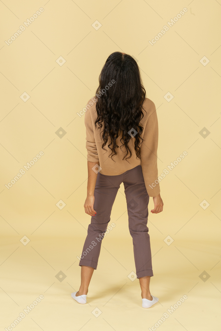 Back view of a tired dark-skinned young female leaning back