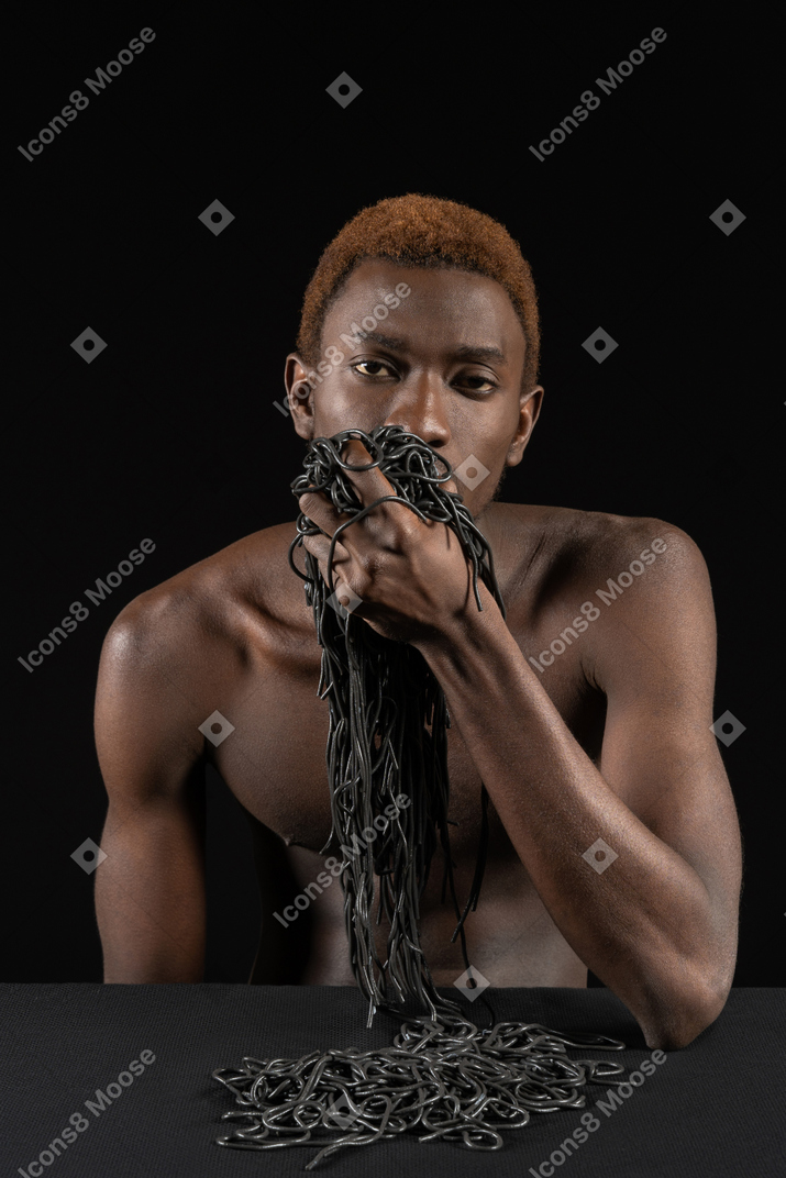一个年轻的非洲人拿着一抱意大利面的前视图