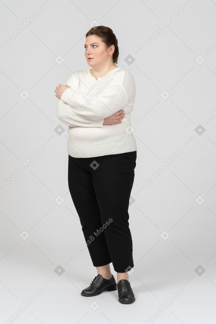 Femme dodue dans des vêtements décontractés en gardant les bras croisés