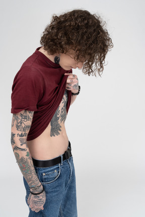 Tattooed boy lifting t-shirt to see his abdomen