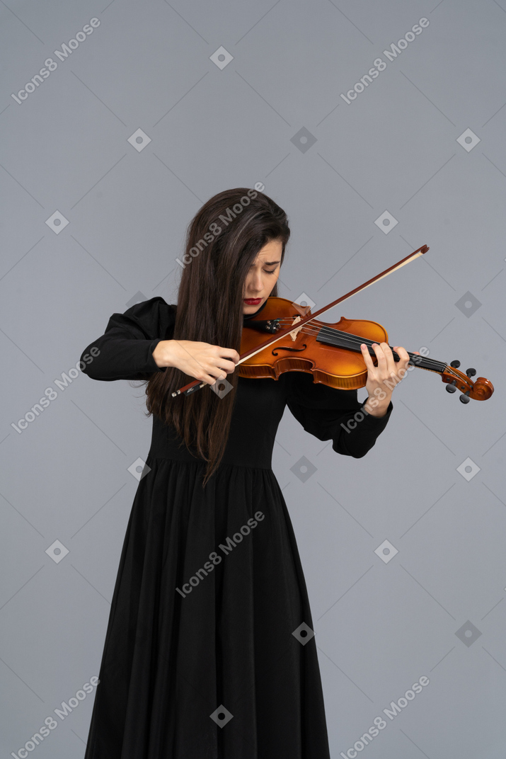 Close-up of a young miserable lady in black dress playing the violin
