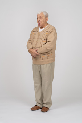 Vista frontal de un anciano con ropa informal que muestra la lengua