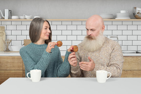 A man and woman sitting at a table eating cookies