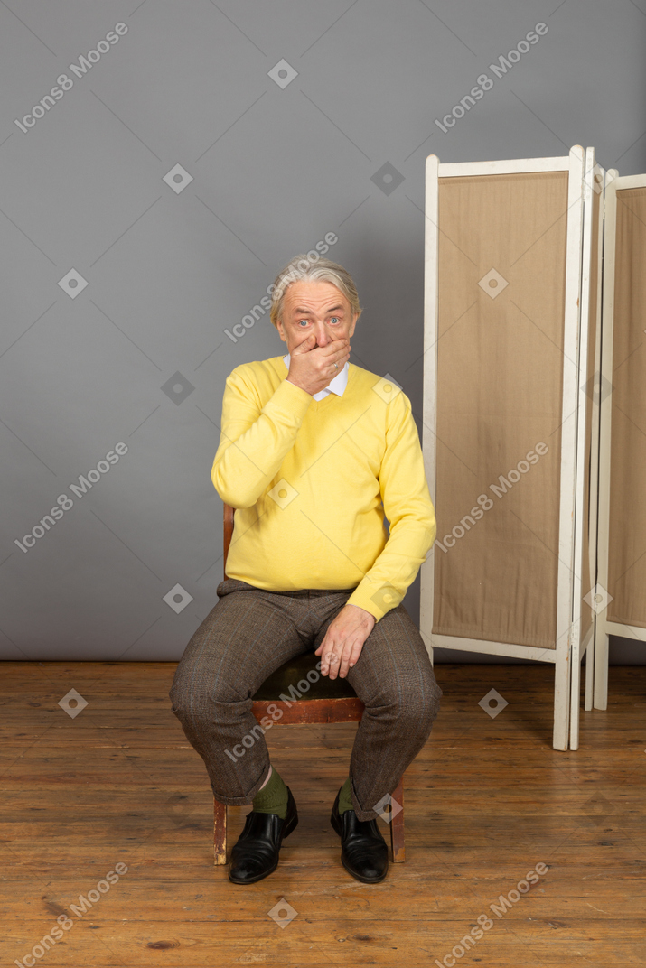 Hombre de mediana edad sentado y tapándose la boca