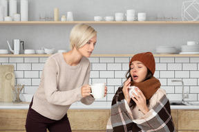Woman giving a mug of tea to a sick friend
