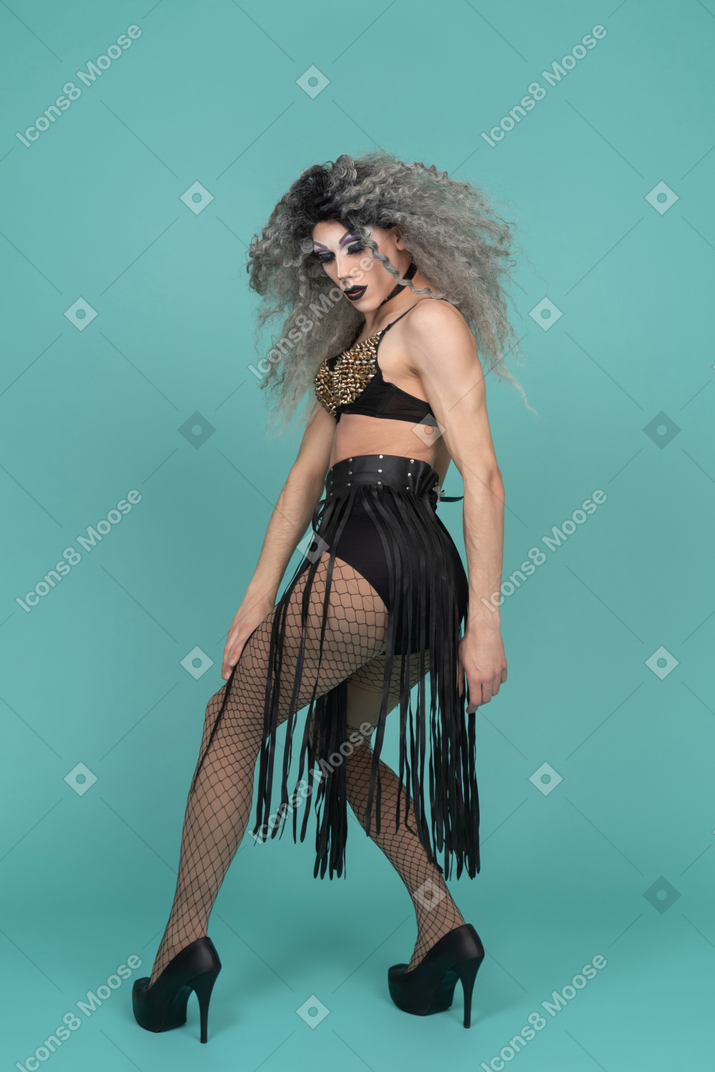 Vista posteriore di una drag queen in completo nero con le ginocchia piegate