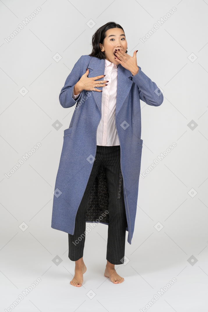 Mujer sorprendida con abrigo cubriendo su boca