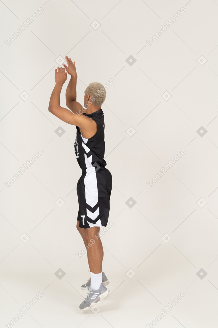 Side view of a young male basketball player throwing something
