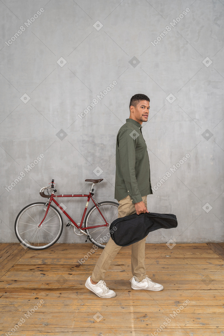 Side view of a man with a ukulele case walking