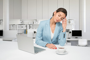 A woman sitting at a table with a laptop and a cup of coffee