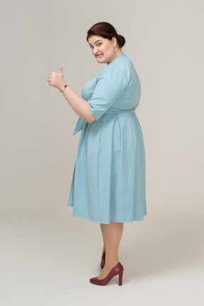 Vista laterale di una donna in abito blu che mostra il pollice in su