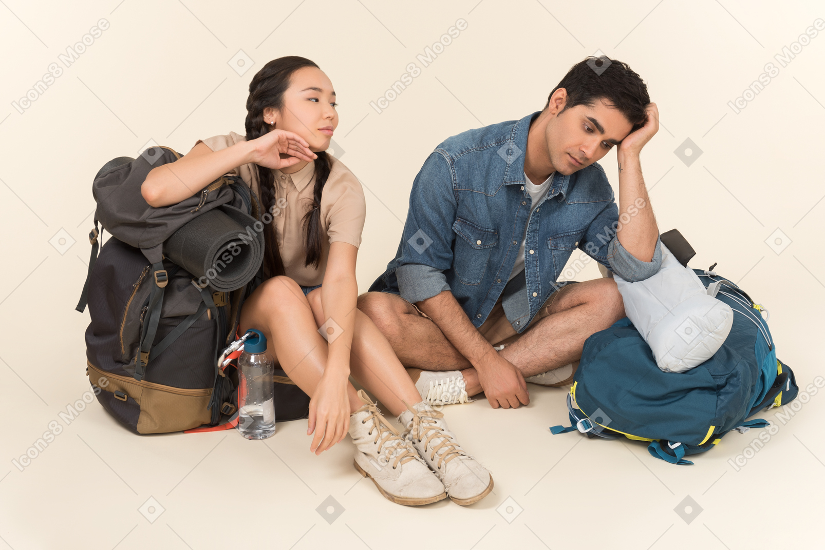 Young interracial couple sitting near huge backpacks