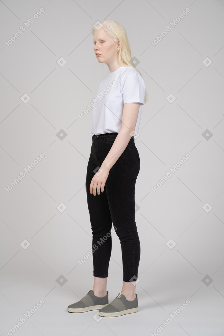 Vista di tre quarti di una giovane donna bionda in abiti casual che guarda da parte