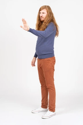 Side view of a young man in casual clothes making stop sign
