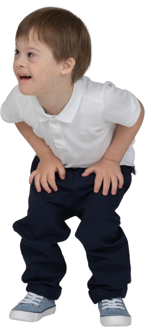 Front view of a boy crouching down and resting his hands on his knees