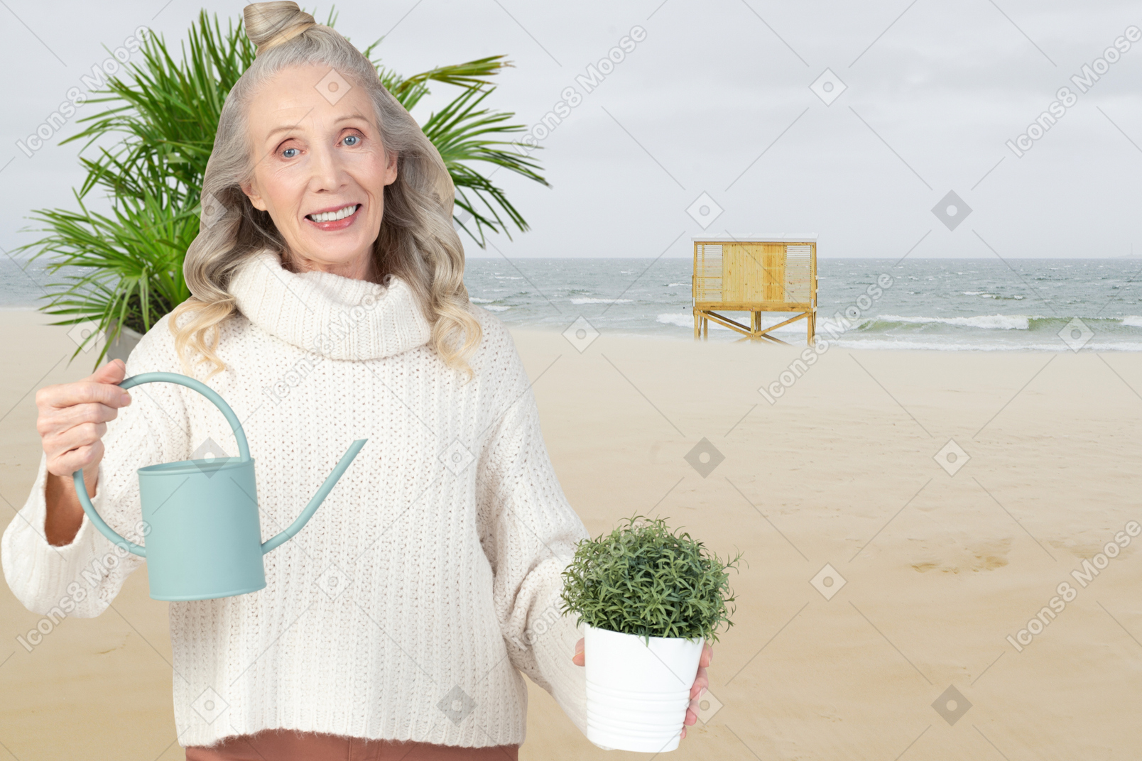 Mujer mayor sosteniendo una regadera y una planta en maceta en el fondo de la playa