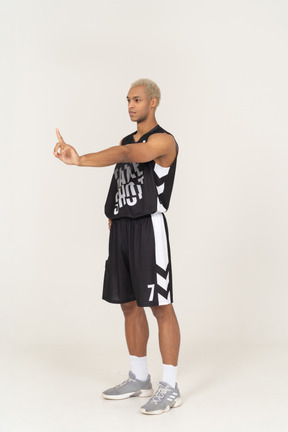 Vista di tre quarti di un giovane giocatore di basket maschile che punta il dito verso l'alto