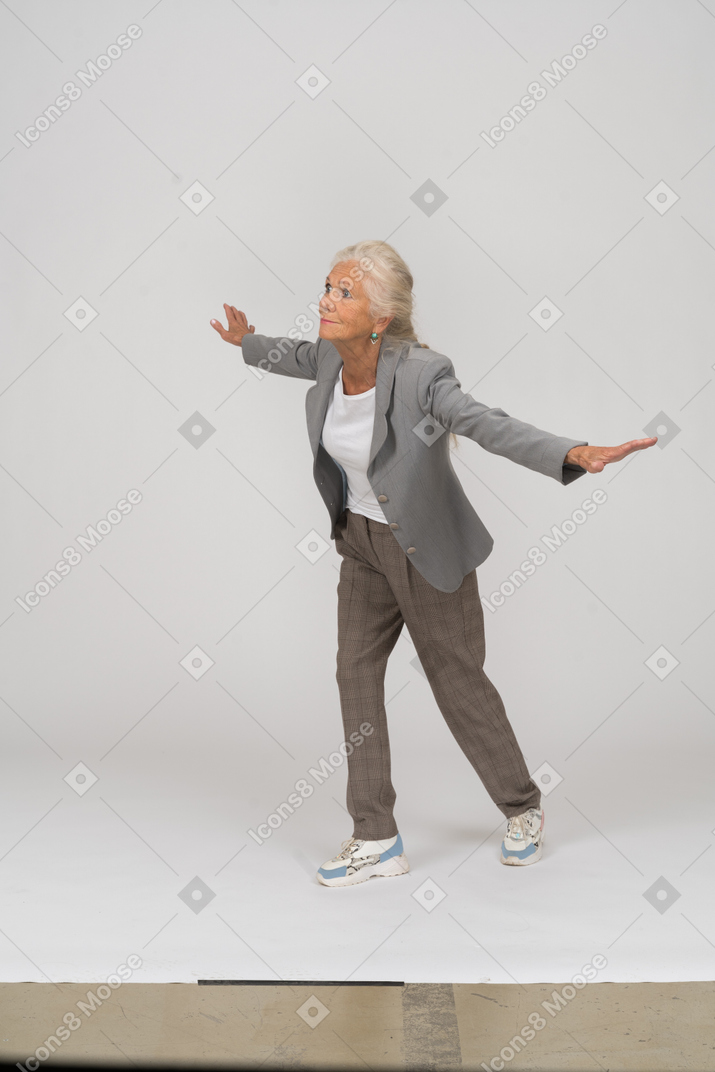 Side view of an old lady in suit standing with outspreading arms