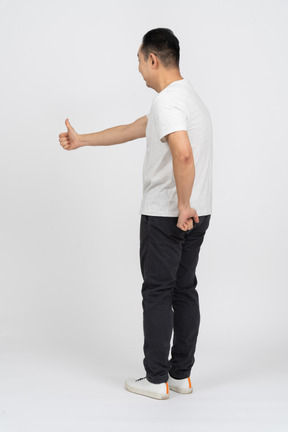 Вид сбоку на человека в повседневной одежде, показывающего большой палец вверх