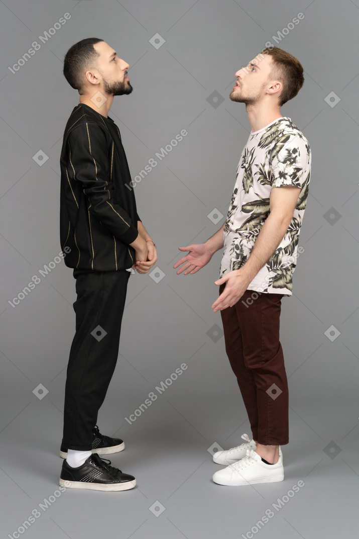Side view of two young men looking up questioningly