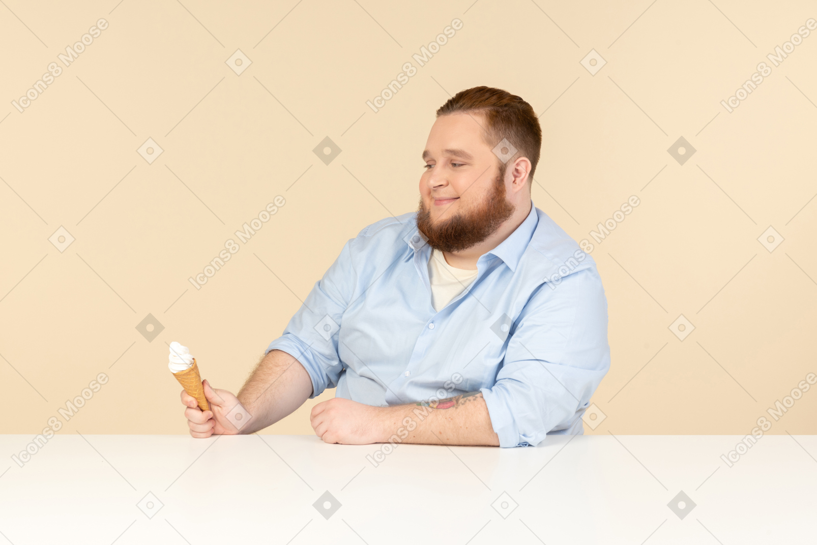テーブルに座って、アイスクリームを保持している大きな男