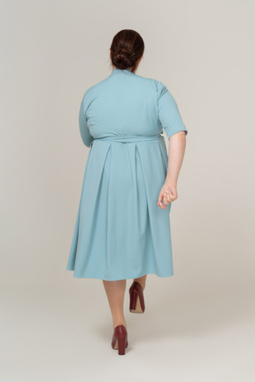 Rear view of a woman in blue dress walking