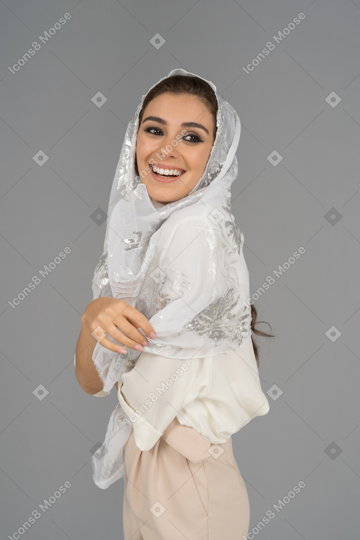 Cheerful young arab woman in white headscarf smiling in profile