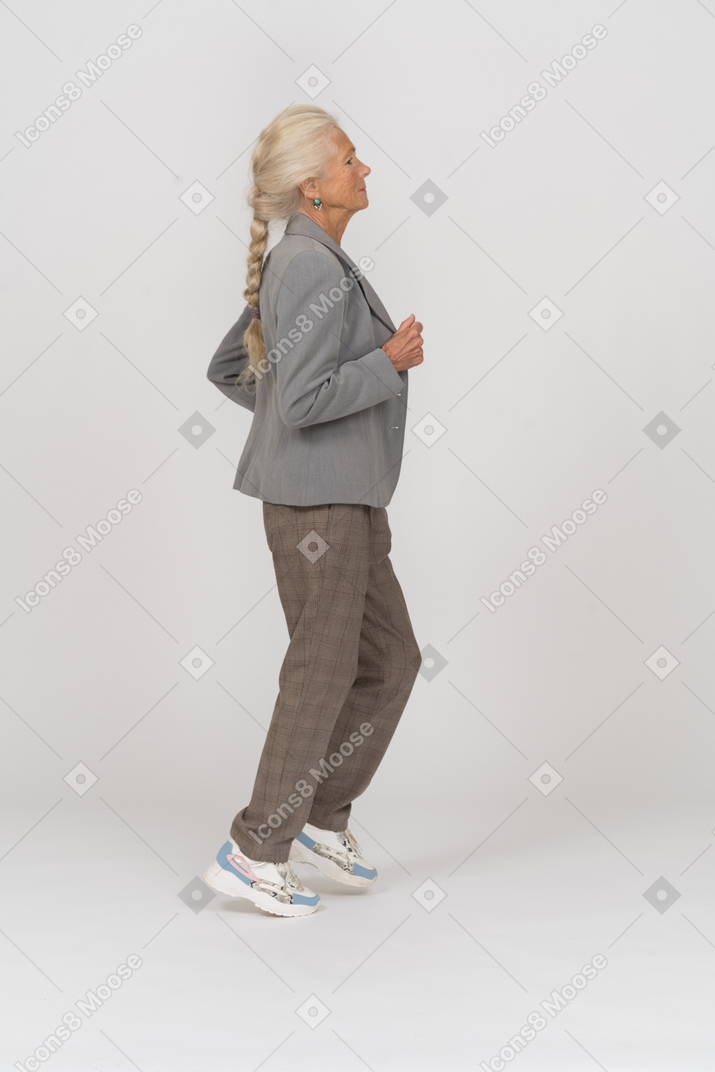 Vista lateral de uma senhora idosa de terno correndo
