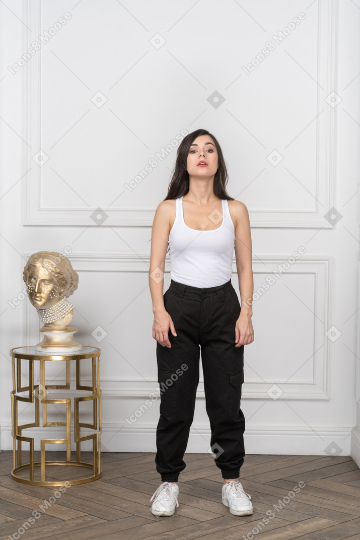 Mujer en camiseta sin mangas de pie con los brazos a los lados