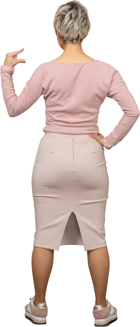 何かの小さいサイズを示すカジュアルな服を着た女性の背面図