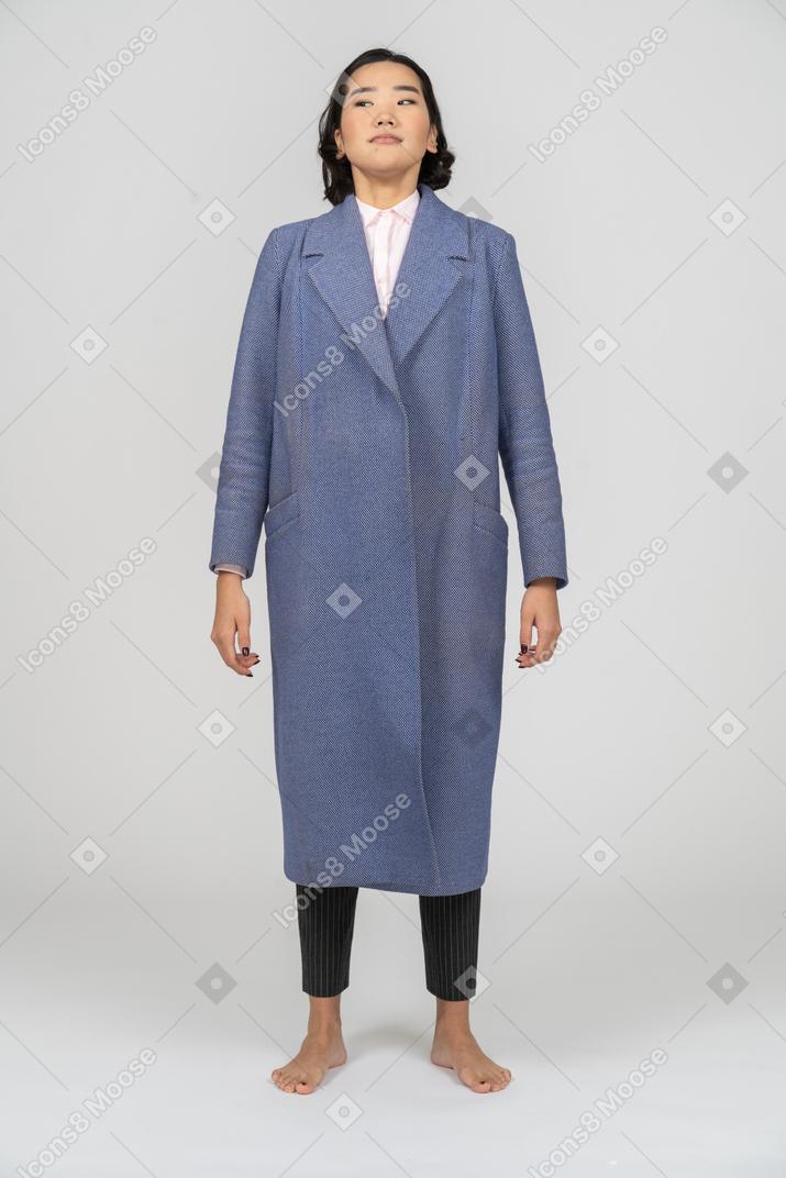 Woman in blue coat standing with arms at sides
