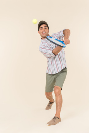 Young caucasian guy throwing ball with tennis racket