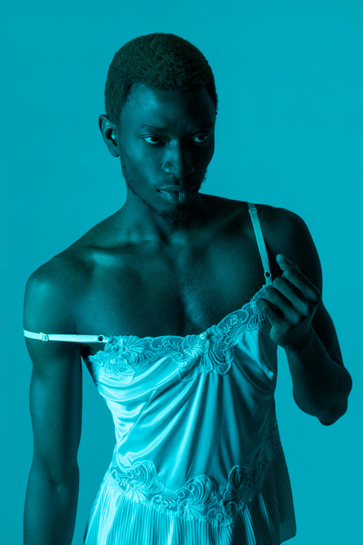 Young black man wearing white nightie in blue light