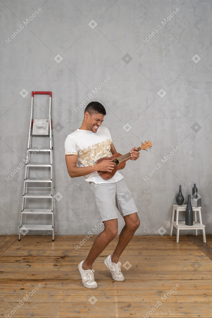 Dreiviertelansicht eines mannes, der auf zehenspitzen auf einer ukulele rockt
