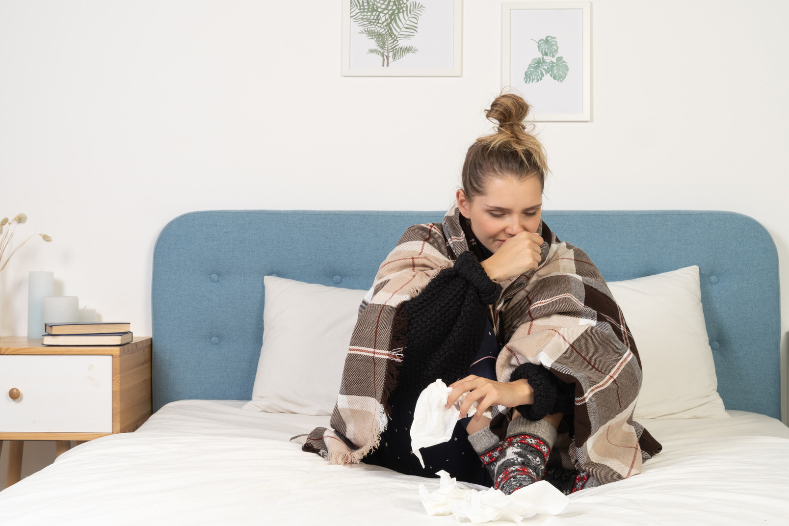 Front view of an ill coughing young lady in pajamas wrapped in checked blanket