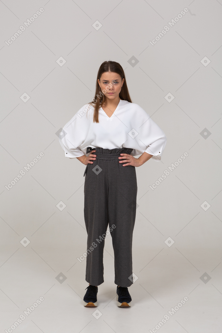 Front view of a serious young lady in office clothing putting hands on hips