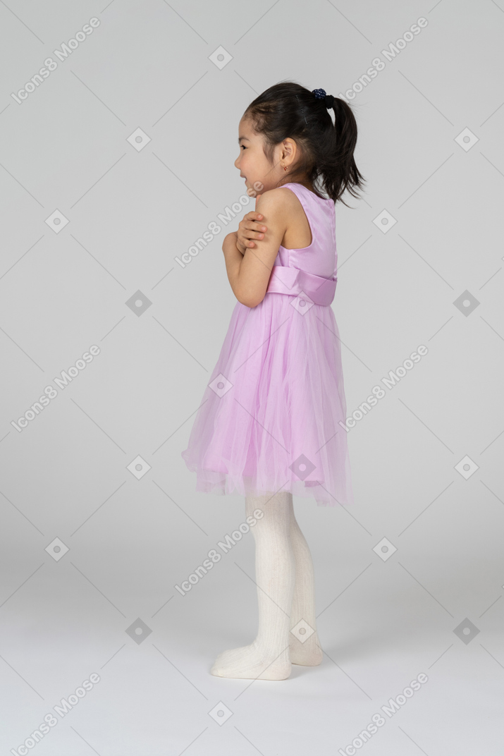 一个小女孩双臂交叉颤抖的侧视图