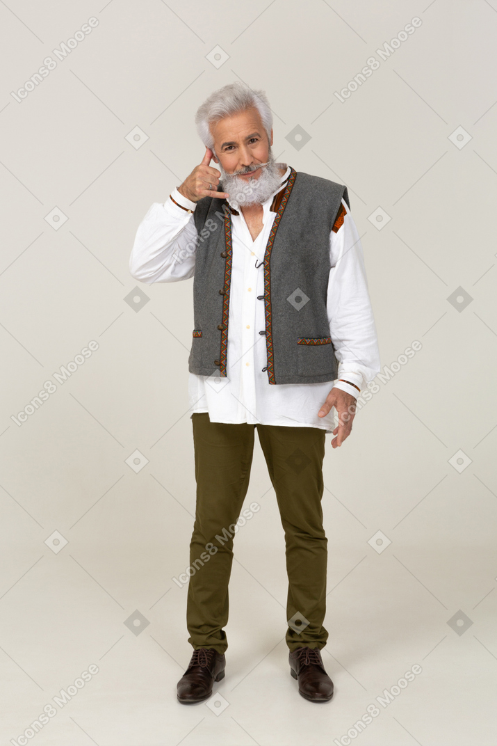 Man in gray vest making "on the phone" gesture