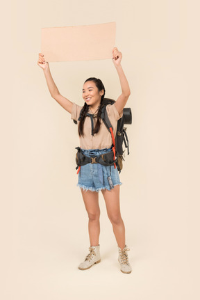 Young female hitchhiker holding up paper card