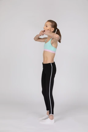 Side view of a teen girl in sportswear raising hand and arguing