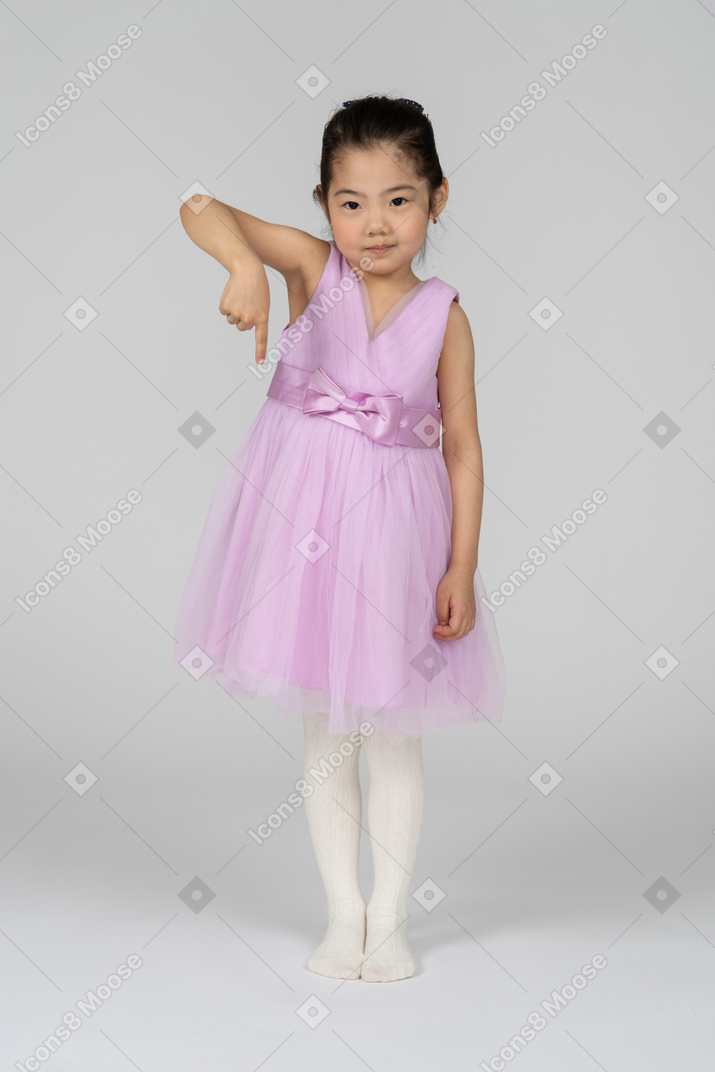 Full length portrait of a cute little girl pointing downwards