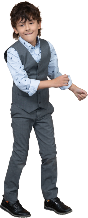 Front view of a cute boy in grey suit dancing and looking at camera