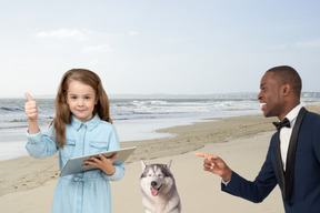 A man and a little girl on a beach with a dog
