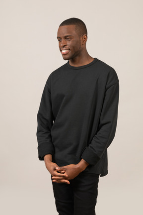 Happy young man standing with folded hands