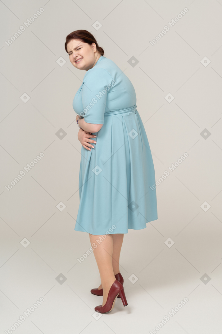 一名身着蓝色连衣裙、胃痛的女人的侧视图