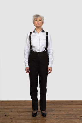 Vista frontal de una anciana en ropa de oficina de pie todavía en la habitación