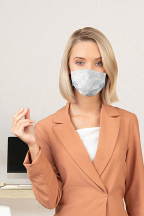 A woman wearing a face mask standing in front of a desk