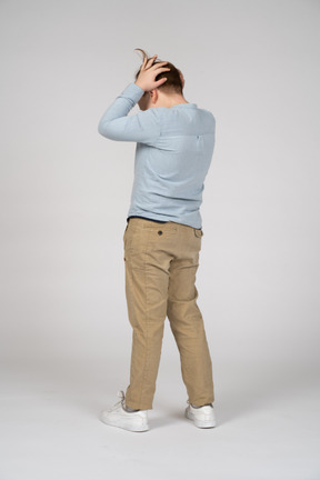 Rear view of a boy standing with hands behind head