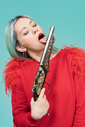 Jolie jeune femme léchant un pistolet